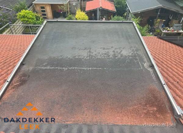Verouderd plat dak met slijtage tussen schuine daken in Leek Verouderd plat dak met slijtage tussen schuine daken in Leek