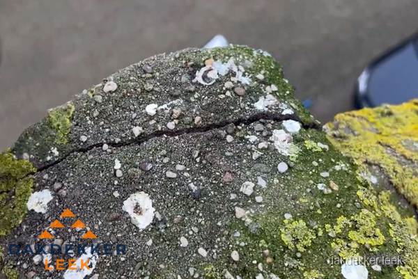 Beschadigde en verweerde nokvorst met scheuren en mos in Leek Beschadigde en verweerde nokvorst met scheuren en mos in Leek