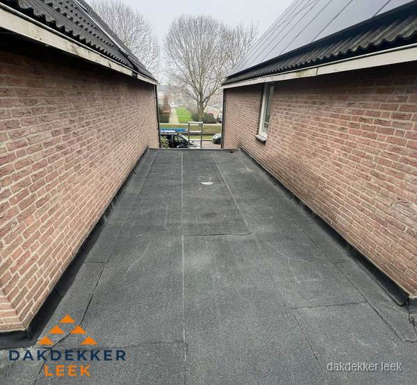 Plat dak met bitumen dakbedekking tussen bakstenen muren in Leek Plat dak met bitumen dakbedekking tussen bakstenen muren in Leek